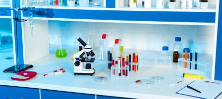 flasks, test tubes and bottles near microscope in modern laboratory