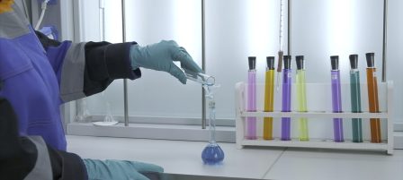 Woman conducts laboratory experiments and analyzes. Clip. Woman looks at chemical liquid in laboratory. Industrial laboratory with workers and chemicals in test tubes.